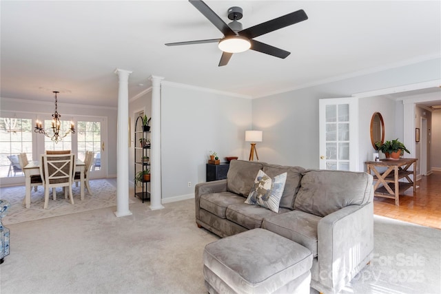 living area featuring light carpet, baseboards, crown molding, ornate columns, and ceiling fan with notable chandelier