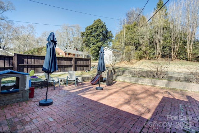 view of patio with a shed, fence, a playground, and an outbuilding