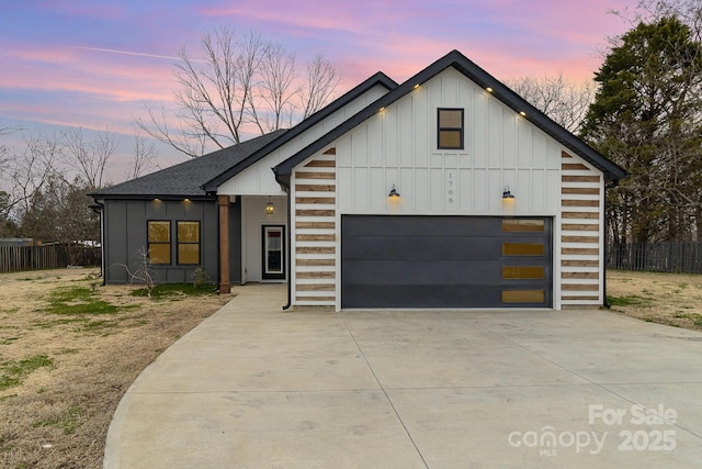 view of front facade featuring driveway, a shingled roof, an attached garage, fence, and board and batten siding