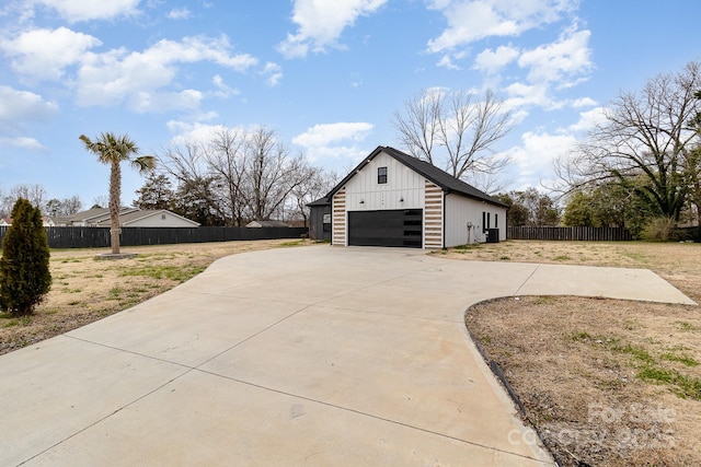 view of home's exterior featuring board and batten siding, fence, and a detached garage