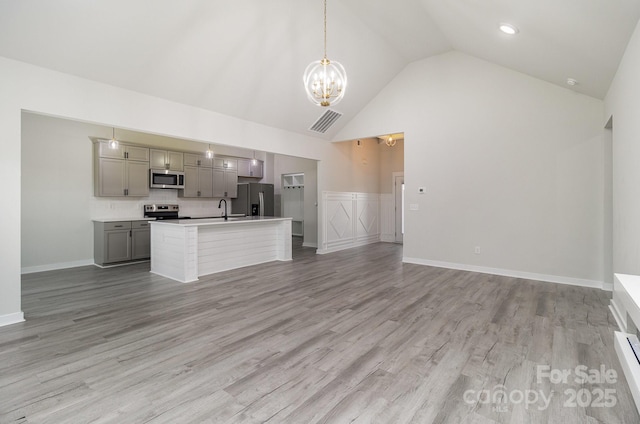 kitchen with gray cabinetry, stainless steel appliances, visible vents, open floor plan, and light countertops