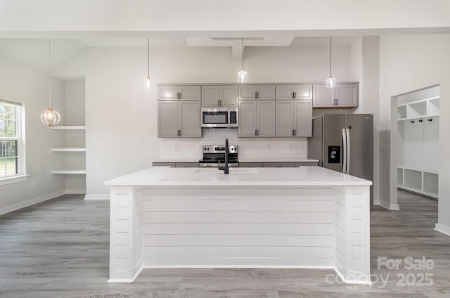 kitchen with stainless steel appliances, gray cabinets, light countertops, and decorative backsplash