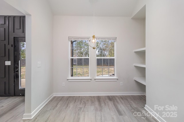 unfurnished dining area with plenty of natural light, baseboards, and wood finished floors