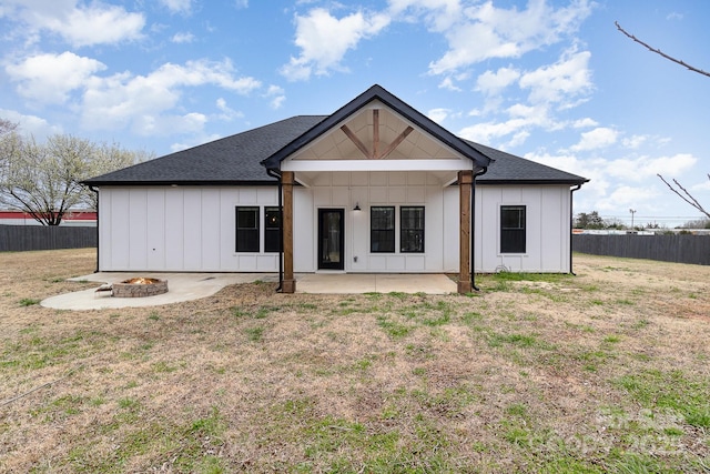 back of property featuring a patio, a lawn, board and batten siding, fence, and a fire pit