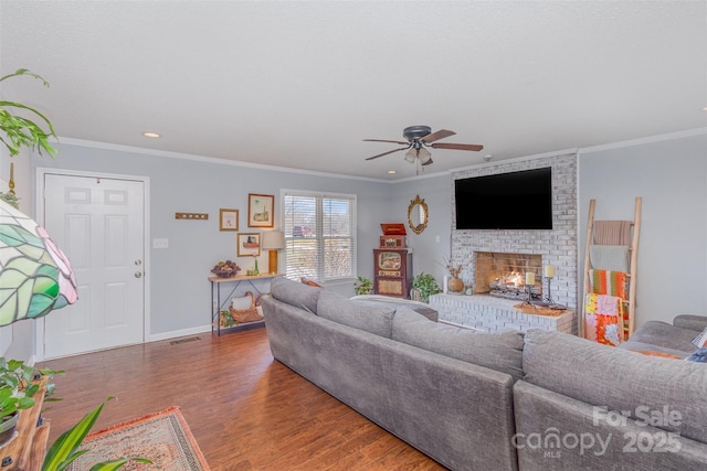 living area featuring dark wood-style floors, ornamental molding, a brick fireplace, and baseboards