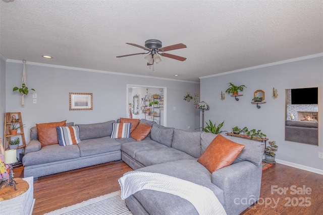 living area featuring a textured ceiling, a warm lit fireplace, dark wood-type flooring, a ceiling fan, and crown molding