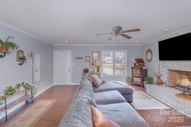 living area featuring baseboards, a fireplace, ornamental molding, and dark wood-style flooring