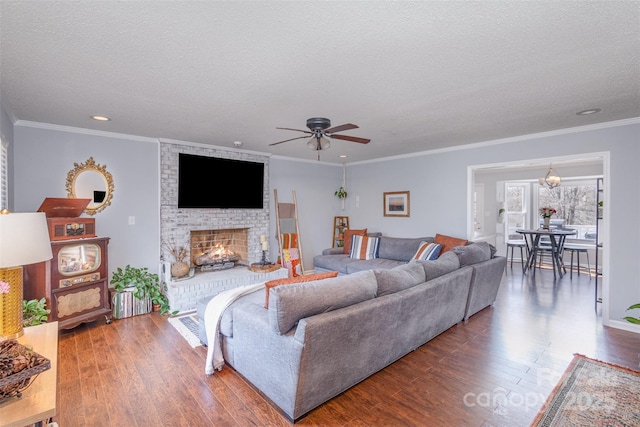 living area featuring a brick fireplace, crown molding, a textured ceiling, and wood finished floors