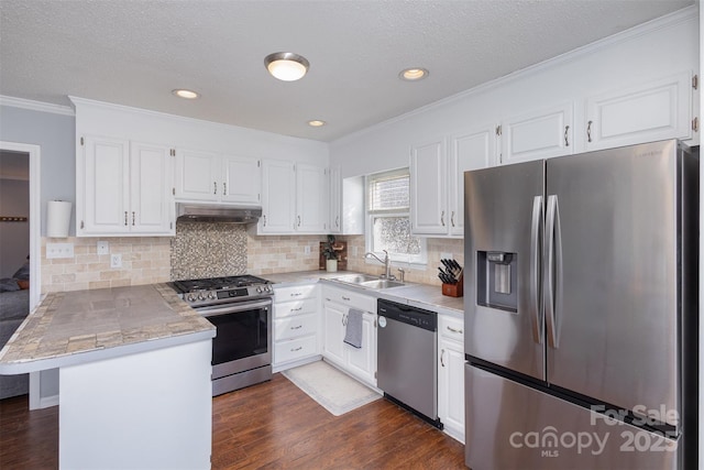 kitchen with tile counters, appliances with stainless steel finishes, white cabinets, a peninsula, and under cabinet range hood