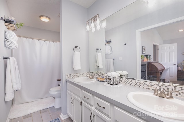 bathroom featuring double vanity, a sink, toilet, and decorative backsplash