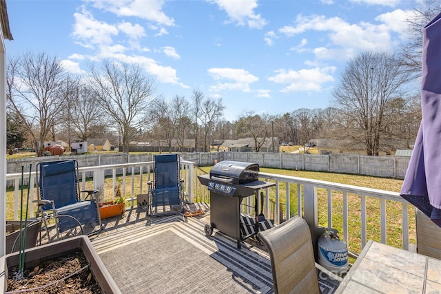 wooden deck with a residential view, a fenced backyard, a grill, and a lawn