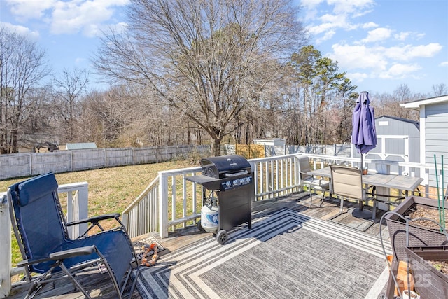 deck with a storage shed, a fenced backyard, grilling area, outdoor dining area, and an outdoor structure