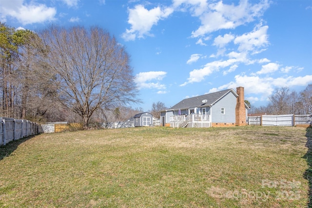 view of yard featuring an outbuilding, a fenced backyard, and a storage unit