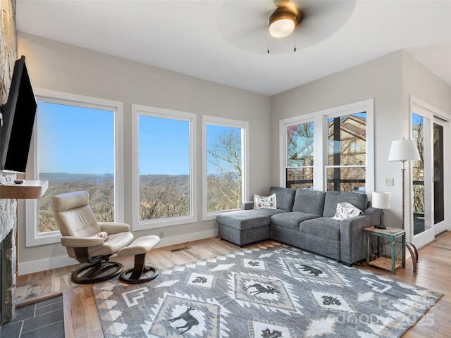 sunroom / solarium with ceiling fan and a fireplace