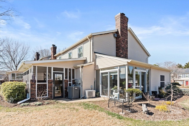 rear view of property with ac unit, central AC unit, a chimney, and a sunroom