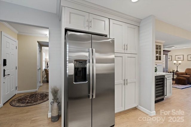 kitchen with wine cooler, white cabinets, light countertops, stainless steel fridge with ice dispenser, and light wood finished floors