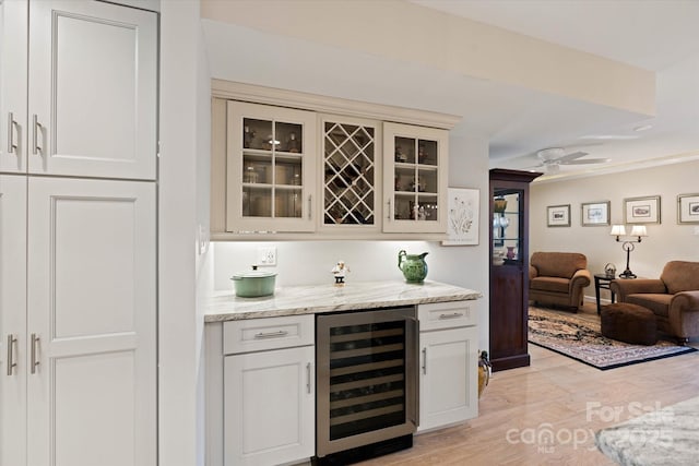 bar with a dry bar, light wood-type flooring, wine cooler, and a ceiling fan