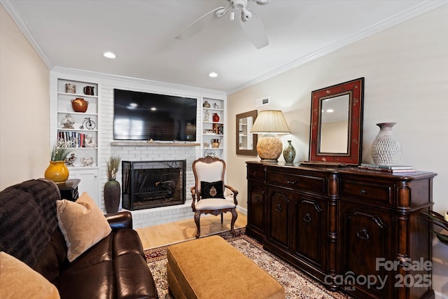 living room featuring light wood-type flooring, built in shelves, a fireplace, and crown molding