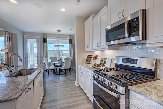 173 Glenn Dr, Mooresville, NC 28115 - kitchen with appliances with stainless steel finishes, a sink, white cabinets, light wood-style flooring, and tasteful backsplash