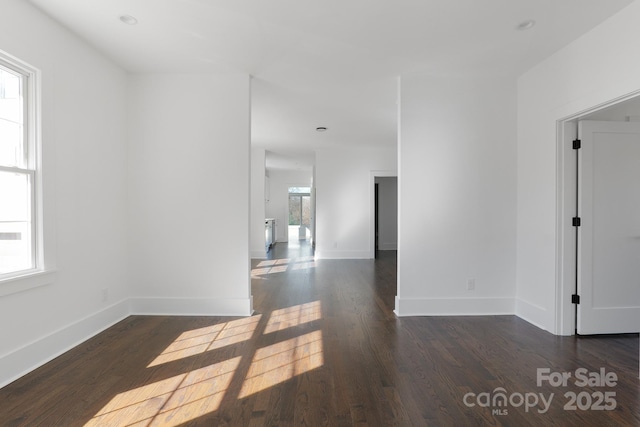 spare room featuring baseboards and dark wood-style flooring