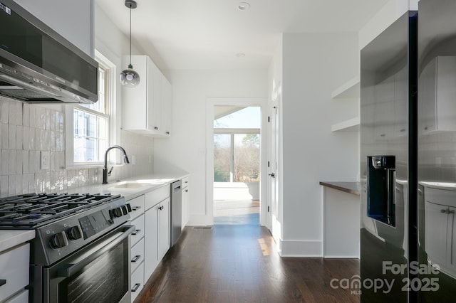 kitchen featuring appliances with stainless steel finishes, decorative light fixtures, white cabinetry, open shelves, and a sink