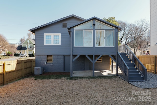 rear view of property featuring central air condition unit, a patio area, a fenced backyard, and brick siding