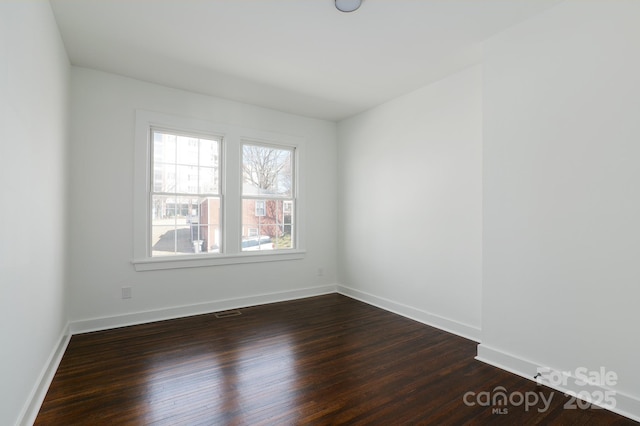 unfurnished room featuring dark wood-style floors and baseboards