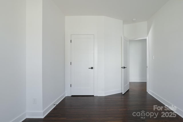 unfurnished bedroom featuring baseboards and dark wood-type flooring