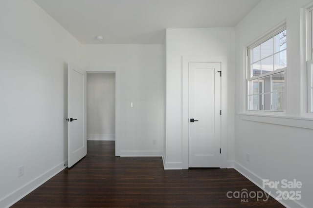 unfurnished bedroom featuring baseboards and dark wood finished floors