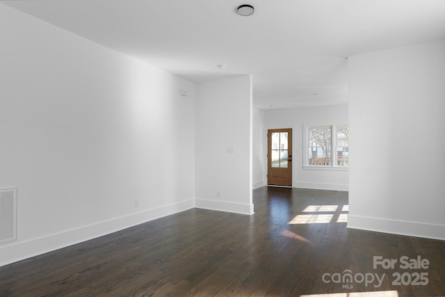 empty room featuring dark wood-style floors and baseboards