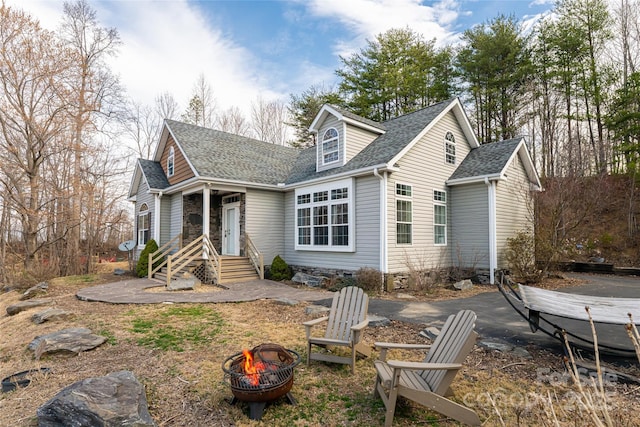 view of front of property with crawl space, roof with shingles, and a fire pit