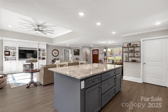 kitchen with gray cabinets, open floor plan, a kitchen island, and light stone counters