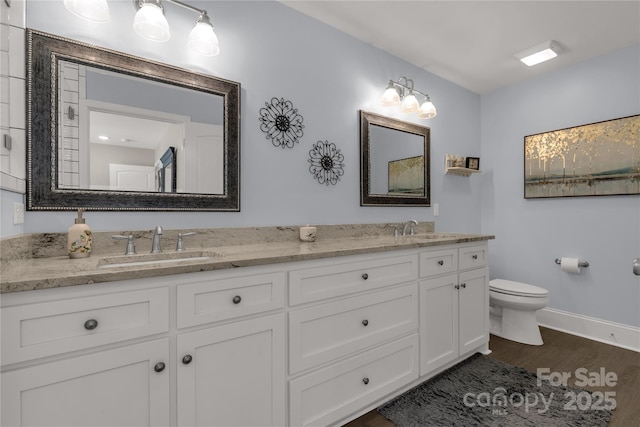 bathroom with double vanity, toilet, a sink, and wood finished floors