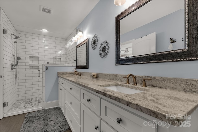 full bath featuring double vanity, a sink, visible vents, and a shower stall