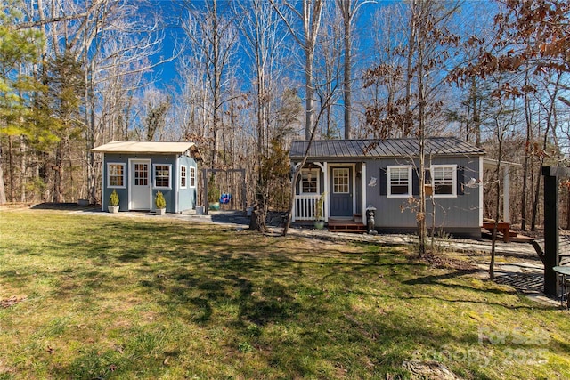 view of front of house featuring an outbuilding, metal roof, a standing seam roof, and a front yard