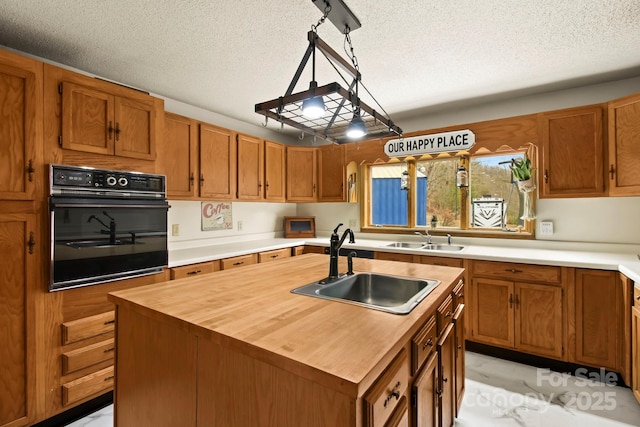 kitchen with hanging light fixtures, an island with sink, and a sink