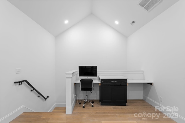 office space with light wood finished floors, baseboards, visible vents, and vaulted ceiling