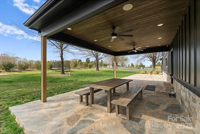 view of patio featuring a trampoline, outdoor dining space, and a ceiling fan