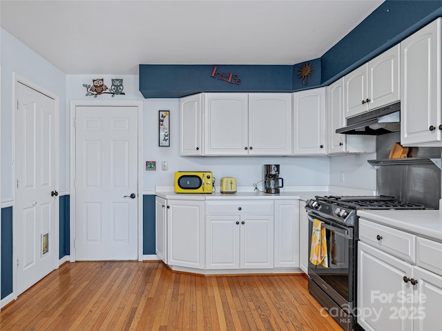 kitchen with light countertops, light wood-style flooring, gas stove, white cabinets, and under cabinet range hood