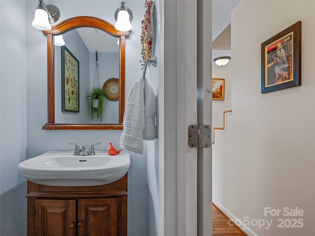 bathroom with wood finished floors, vanity, and baseboards