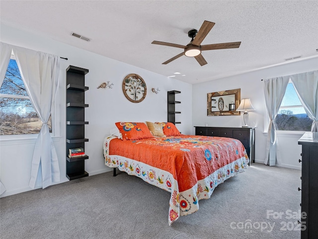 carpeted bedroom with a textured ceiling, ceiling fan, visible vents, and baseboards