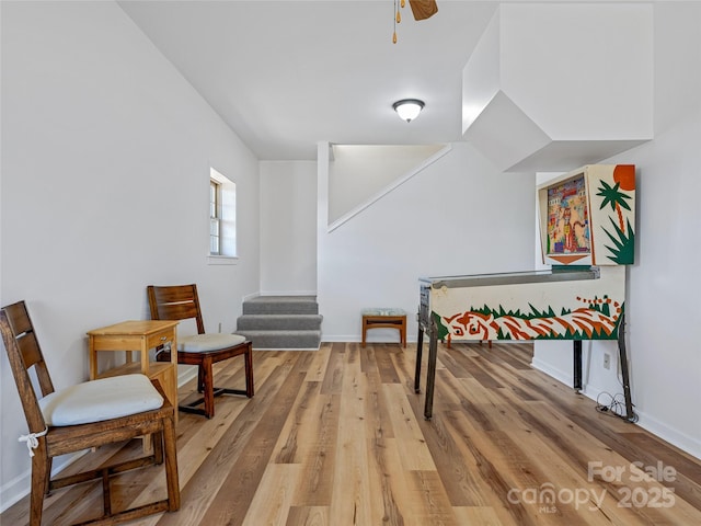 game room featuring light wood finished floors, ceiling fan, and baseboards