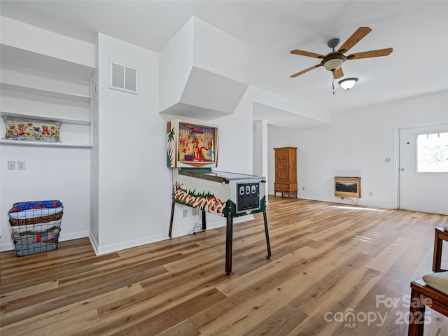 recreation room featuring visible vents, ceiling fan, light wood-style flooring, and heating unit