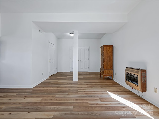 interior space featuring heating unit, light wood finished floors, visible vents, and baseboards