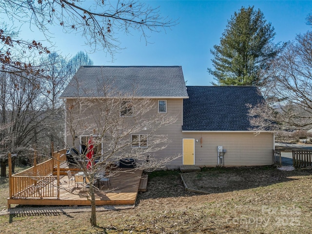 back of property with a shingled roof and a wooden deck