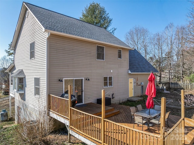 back of house with outdoor dining area, roof with shingles, and a deck