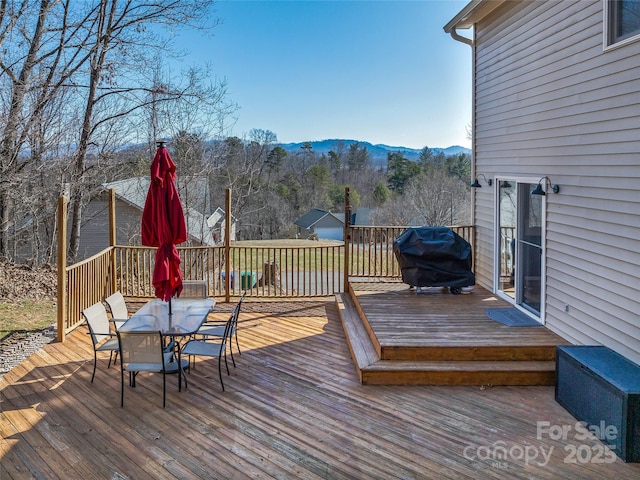 wooden deck featuring a mountain view, grilling area, and outdoor dining space