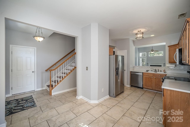 kitchen with brown cabinets, decorative light fixtures, stainless steel appliances, light countertops, and visible vents