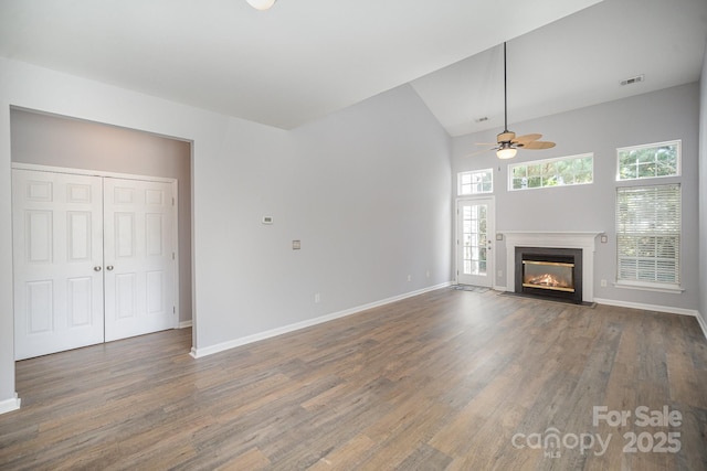 unfurnished living room featuring dark wood-style flooring, a fireplace with flush hearth, and baseboards