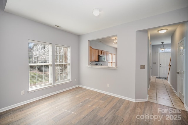 unfurnished room featuring light wood-style floors, visible vents, and baseboards